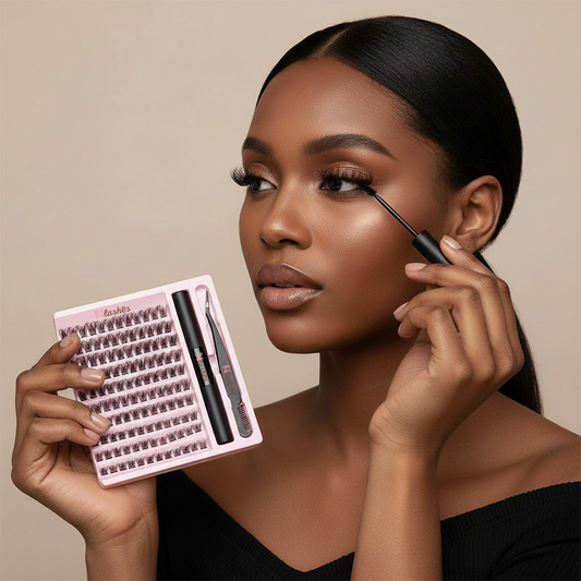 A woman with dark hair pulled back applies false eyelashes while holding a pink tray of lashes and a black eyeliner pencil. The background is a solid warm beige studio backdrop.