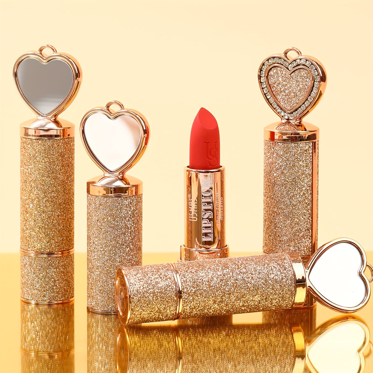 Set of glittery lipsticks with heart-shaped mirrors on a yellow background
